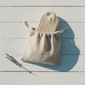 Linen drawstring pouch flat lay with oat sock on sun-bleached wood